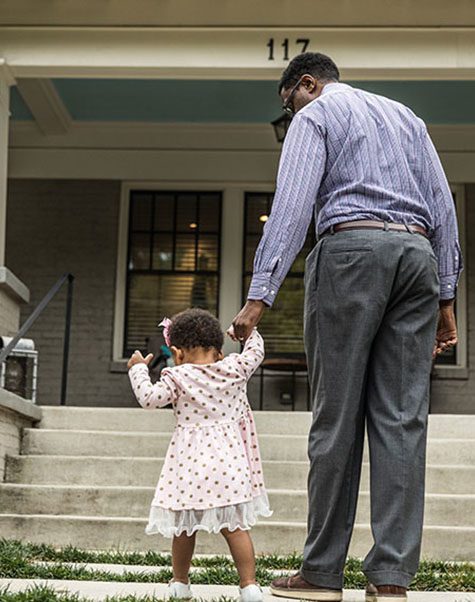 dad holding daugters hand in front of house