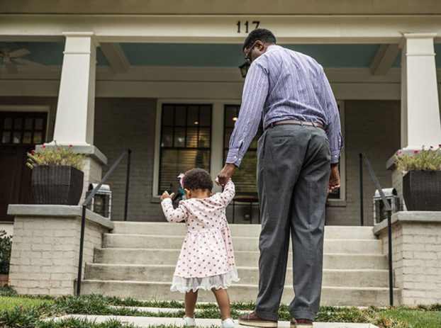 dad holding daugters hand in front of house