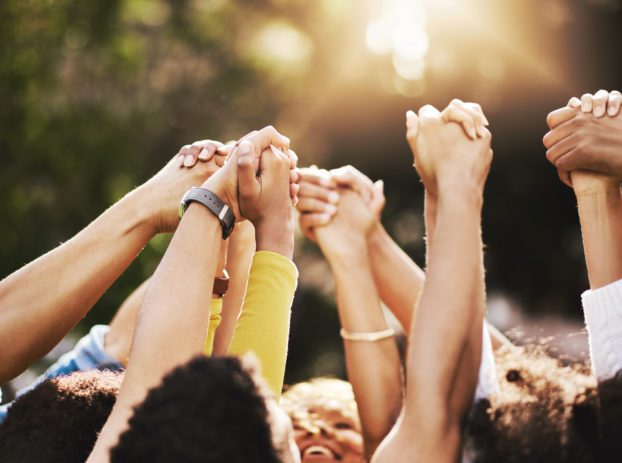 group of people holding each others hand in the air