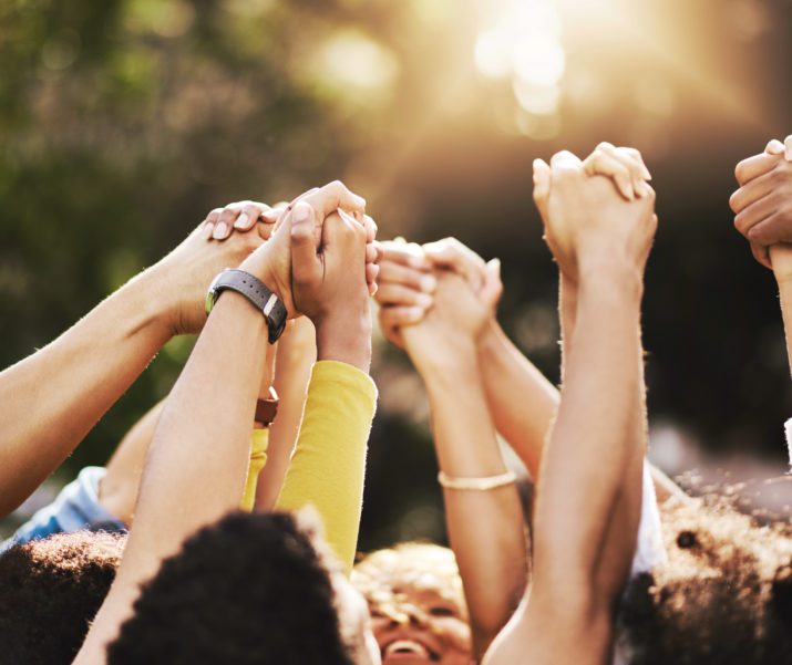 group of people holding each others hand in the air