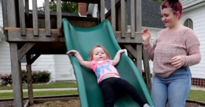 Young child on slide with parent supervising