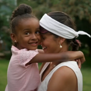 woman in white tank top holding a young girl in a pink shirt