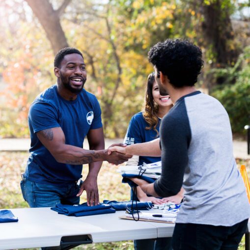Mid adult man shakes hands with unrecognizable volunteer