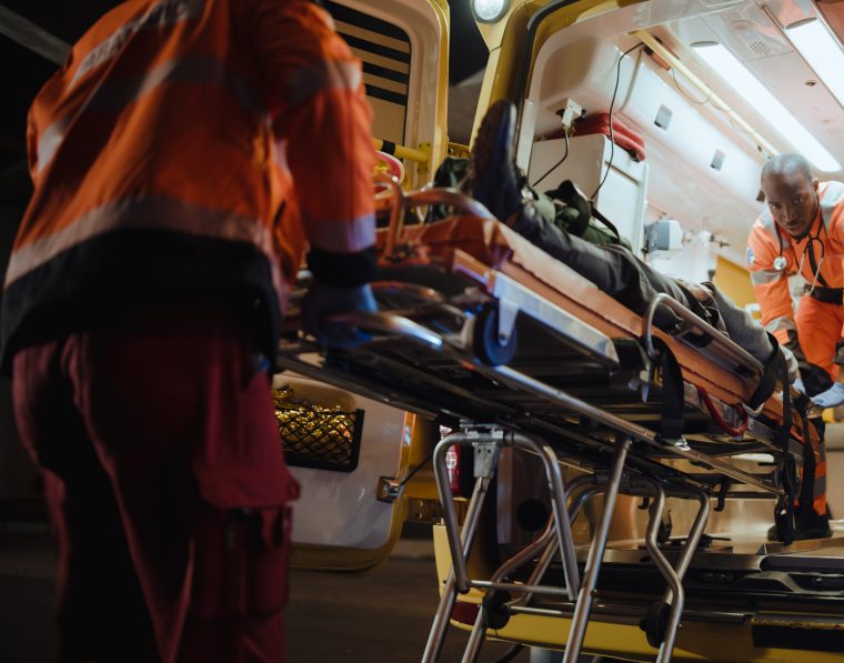 Team of EMS Paramedics React Quick to Bring Injured Patient to Healthcare Hospital and Get Him Out of Ambulance on a Stretcher. Emergency Care Assistants Help Young Man to Stay Alive After Accident.